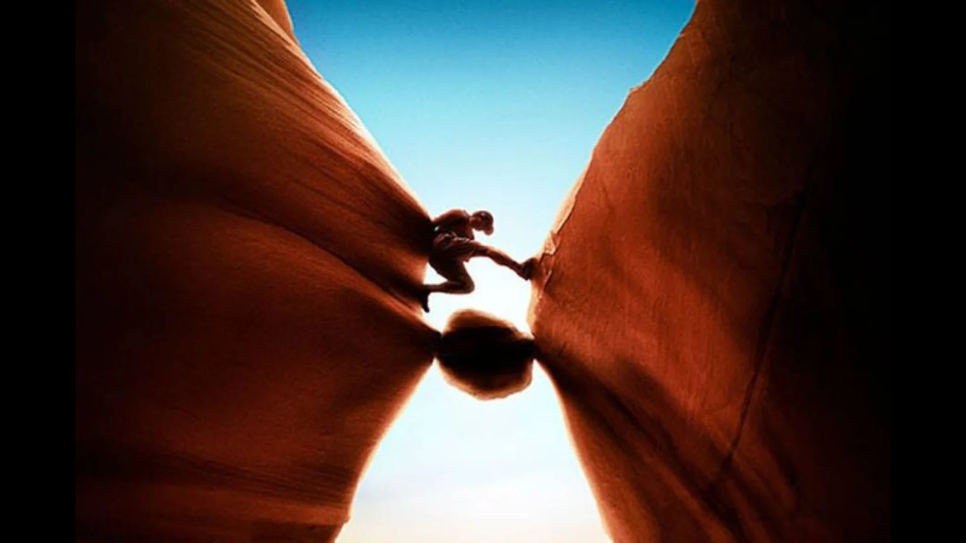 Jovem se segurando com as pernas entre duas rochas em um canyon